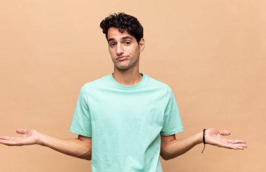 Genç yakışıklı adam şaşkın ve şaşkın hissediyor, doğru cevap veya karardan emin değil, bir seçim yapmaya çalışıyor.