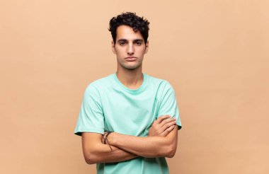 Genç yakışıklı adam hayal kırıklığına uğramış ve hayal kırıklığına uğramış, ciddi görünüyor, kızgın ve kollarını kavuşturmuş.