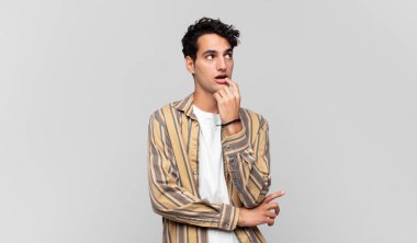 Şaşırmış, gergin, endişeli ya da korkmuş bakışları olan genç yakışıklı bir adam kopya boşluğuna bakıyor.