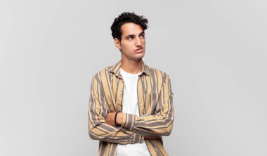 Genç yakışıklı adam şüphe ediyor ya da düşünüyor, dudağını ısırıyor ve kendini güvensiz ve gergin hissediyor, kenarda yer arıyor.