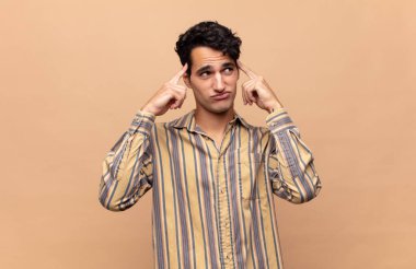 Genç ve yakışıklı bir adam kafası karışmış ya da şüphe içinde, bir fikre odaklanmış, çok düşünüyor, kenarda boşluğu kopyalamaya çalışıyor.