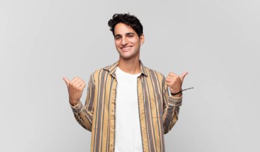 Genç ve yakışıklı adam neşeyle gülümsüyor ve mutlu görünüyor, kaygısız ve pozitif hissediyor.