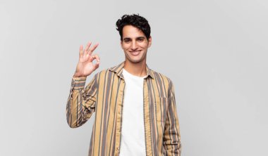 Genç yakışıklı adam mutlu, rahat ve tatmin olmuş hissediyor. Onayını iyi bir hareketle gösteriyor. Gülümsüyor.