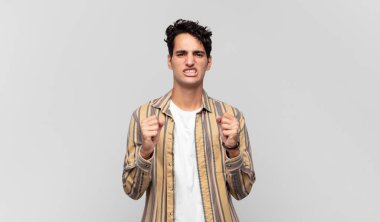 Genç yakışıklı adam sinirli, sinirli, sinirli bakışlar ve sıkı yumruklar ile agresif bir şekilde bağırıyor.