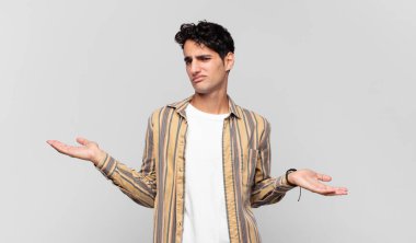 Şaşkın, şaşkın ve stresli görünen genç bir adam. Farklı seçenekler arasında merak ediyor. Belirsiz hissediyor.