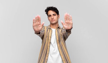 Genç yakışıklı adam ciddi, mutsuz, kızgın ve hoşnutsuz görünüyor. Ya da her iki avuçta da dur diyor.