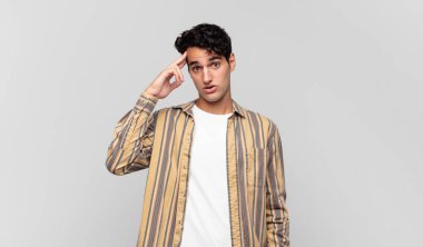 Genç yakışıklı adam mutlu, şaşkın ve şaşırmış görünüyor, gülümsüyor ve inanılmaz ve inanılmaz iyi haberleri fark ediyor.