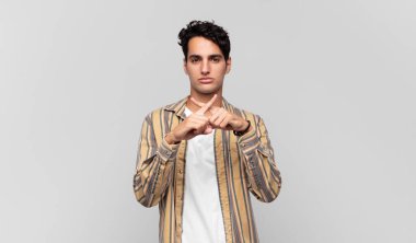 Genç ve yakışıklı bir adam ciddi ve hoşnutsuz görünüyor. İki parmağın önde olsun, reddedilsin ve sessizlik istesin.