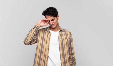 Genç yakışıklı adam stresli, yorgun ve hayal kırıklığına uğramış, alnından ter damlayan, umutsuz ve bitkin hisseden.