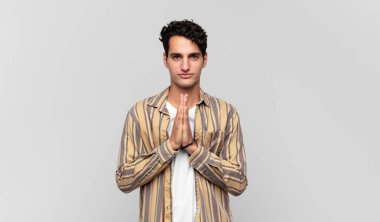 Genç, yakışıklı, endişeli, umutlu ve dindar bir adam. Avuçlarına bastırılmış, af dileyen sadık bir şekilde dua ediyor.