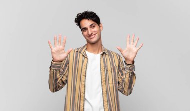 Genç yakışıklı adam gülümsüyor ve arkadaş canlısı görünüyor, onuncu veya onuncu numarayı gösteriyor, eli önde, geriye doğru sayıyor.