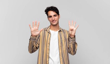 Genç yakışıklı adam gülümsüyor ve arkadaş canlısı görünüyor. 9 ya da 9 numarayı gösteriyor. Elleri önde, geriye doğru sayıyor.