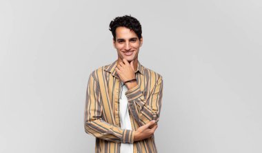 Genç yakışıklı adam gülümsüyor, hayattan zevk alıyor, mutlu, arkadaş canlısı, tatmin olmuş ve tasasız.