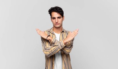 Genç ve yakışıklı adam senin tavırlarından rahatsız ve bıkkın görünüyor, yeter artık! Eller önde çapraz, durmanı söylüyor.