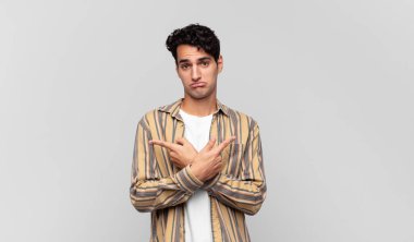 Şaşkın, kafası karışmış, güvensiz ve şüpheyle zıt yönlere bakan genç yakışıklı bir adam.