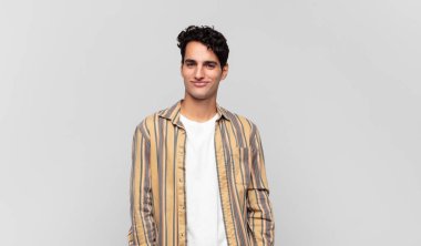 Genç yakışıklı adam pozitif ve kendinden emin gülümsüyor. Tatmin olmuş, arkadaş canlısı ve mutlu görünüyor.