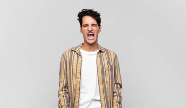 Genç yakışıklı adam agresif bir şekilde bağırıyor, çok kızgın, hayal kırıklığına uğramış, öfkeli ya da sinirli görünüyor, hayır