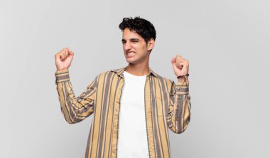 Genç yakışıklı adam zaferle bağırıyor. Heyecanlı, mutlu ve şaşırmış görünüyor. Kutlama yapıyor.