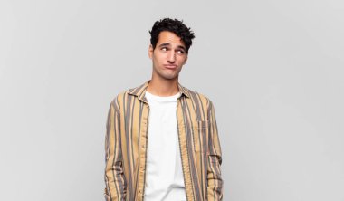 Genç ve yakışıklı adam kafası karışmış görünüyor, merak ediyor ya da bir sorunu çözmeye çalışıyor ya da düşünüyor.