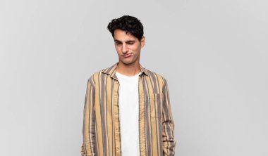 Genç yakışıklı adam mutlu ve arkadaş canlısı görünüyor, gülümsüyor ve sana olumlu bir tavırla göz kırpıyor.