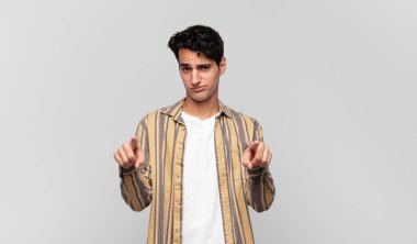 Genç ve yakışıklı bir adam kameraya hem parmaklarını hem de kızgın yüzünü göstererek sana görevini yapmanı söylüyor.