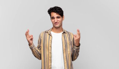 Genç yakışıklı adam endişeyle dua ediyor ve endişeli bir bakışla iyi şanslar diliyor.