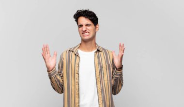 Genç yakışıklı adam öfkeyle bağırıyor, stresli hissediyor ve ellerini havaya kaldırıp neden ben diye bağırıyor.