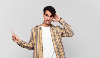 Genç yakışıklı adam gülüyor, mutlu, pozitif ve şaşırmış görünüyor. Yan fotokopi alanını işaret eden harika bir fikrin farkına varıyor.