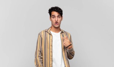 Şok olmuş ve ağzı açık, kendini işaret eden genç yakışıklı bir adam.