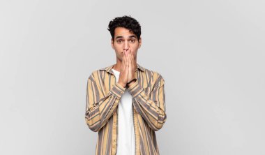 Genç yakışıklı adam mutlu ve heyecanlı, şaşırmış ve şaşırmış elleri ağızda, tatlı bir ifadeyle kıkırdıyor.