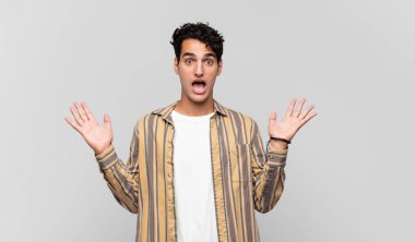 Genç yakışıklı adam mutlu ve heyecanlı görünüyor. Beklenmedik bir sürprizle şoke olmuş. İki eli yüzü açık.