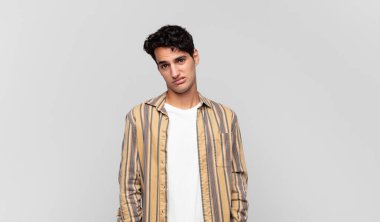 Genç yakışıklı adam şaşkın ve şaşkın hissediyor, aptal, afallamış bir ifadeyle beklenmedik bir şeye bakıyor.