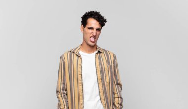 Genç yakışıklı adam tiksinmiş ve rahatsız olmuş hissediyor. Dilini dışarı çıkarıyor. İğrenç ve iğrenç bir şeyden hoşlanmıyor.