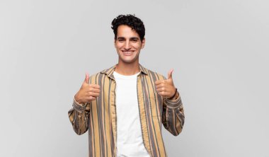 Genç yakışıklı adam gülümsüyor. Mutlu, pozitif, kendinden emin ve başarılı görünüyor.