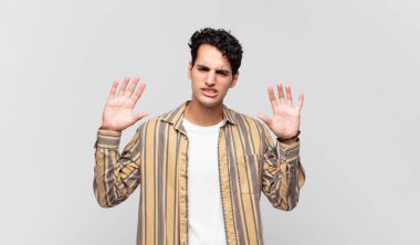 Genç ve yakışıklı bir adam panik ya da öfke içinde bağırıyor, şok olmuş, korkmuş ya da öfkeli, elleri başının yanında.