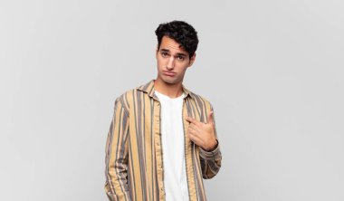 Kafası karışmış, kafası karışmış ve kendine güveni olmayan genç yakışıklı bir adam kendini göstererek kim olduğunu soruyor, ben mi??