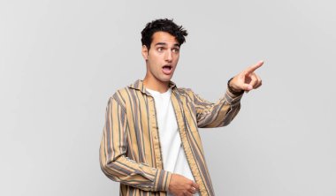 Genç yakışıklı adam şaşkın ve şaşırmış hissediyor, hayranlıkla yukarı bakıyor, şaşırmış, ağzı açık bakıyor.