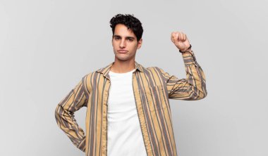 Genç yakışıklı adam ciddi, güçlü ve asi hissediyor, yumruğunu kaldırıyor, protesto ediyor ya da devrim için savaşıyor.