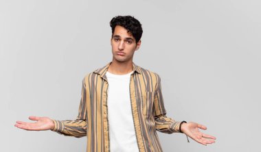 Genç yakışıklı adam şaşkın ve şaşkın hissediyor, doğru cevap veya karardan emin değil, bir seçim yapmaya çalışıyor.