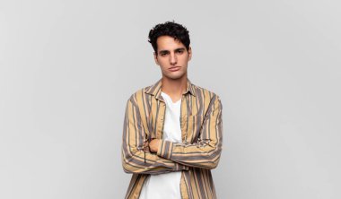 Genç yakışıklı adam hayal kırıklığına uğramış ve hayal kırıklığına uğramış, ciddi görünüyor, kızgın ve kollarını kavuşturmuş.