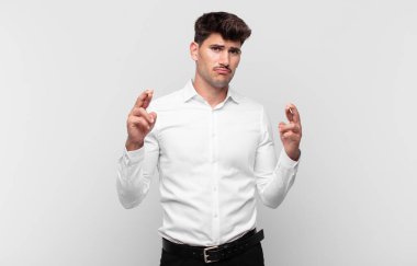 Genç yakışıklı adam endişeyle dua ediyor ve endişeli bir bakışla iyi şanslar diliyor.