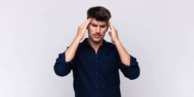 Genç ve yakışıklı bir adam stresli ve hayal kırıklığına uğramış görünüyor. Baskı altında çalışıyor ve sorunları var.