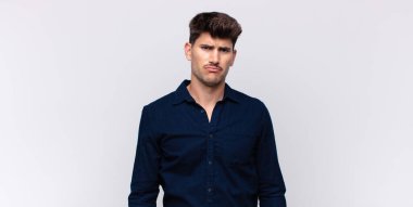 Genç yakışıklı adam üzgün ve mızmız, mutsuz bir bakışla, olumsuz ve hayal kırıklığına uğramış bir tavırla ağlıyor.