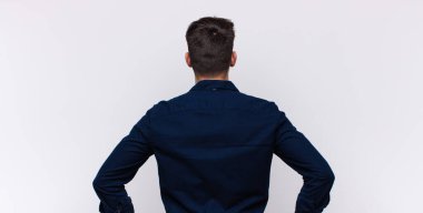 Genç, yakışıklı bir adam kafası karışık ya da dolu ya da şüphe ve soru dolu, merak ediyor, elleri kalçasında, dikiz aynasından.