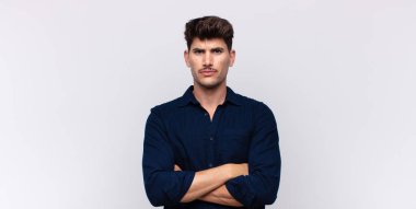 Genç yakışıklı adam hayal kırıklığına uğramış ve hayal kırıklığına uğramış, ciddi görünüyor, kızgın ve kollarını kavuşturmuş.