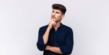 Genç yakışıklı adam düşünceli, meraklı ya da hayal kuruyor, hayal kuruyor ve mekanı kopyalamak için yukarı bakıyor.