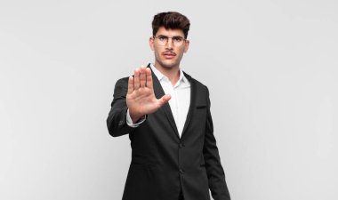 Genç ve yakışıklı adam ciddi, sert, hoşnutsuz ve kızgın görünüyor.