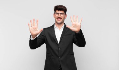 Genç yakışıklı adam gülümsüyor ve arkadaş canlısı görünüyor, onuncu veya onuncu numarayı gösteriyor, eli önde, geriye doğru sayıyor.