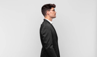 Profil görünümündeki genç yakışıklı adam ilerideki boşluğu kopyalamaya çalışıyor, düşünüyor, hayal ediyor ya da hayal kuruyor.