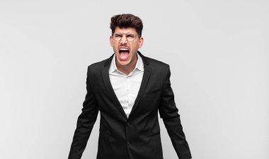 Genç yakışıklı adam agresif bir şekilde bağırıyor, çok kızgın, hayal kırıklığına uğramış, öfkeli ya da sinirli görünüyor, hayır